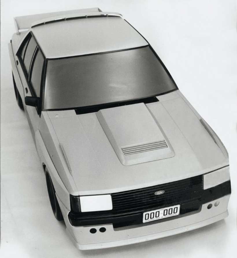 Vista superior de un coche de estilo deportivo en color gris, con un diseño aerodinámico y distintivos faros.